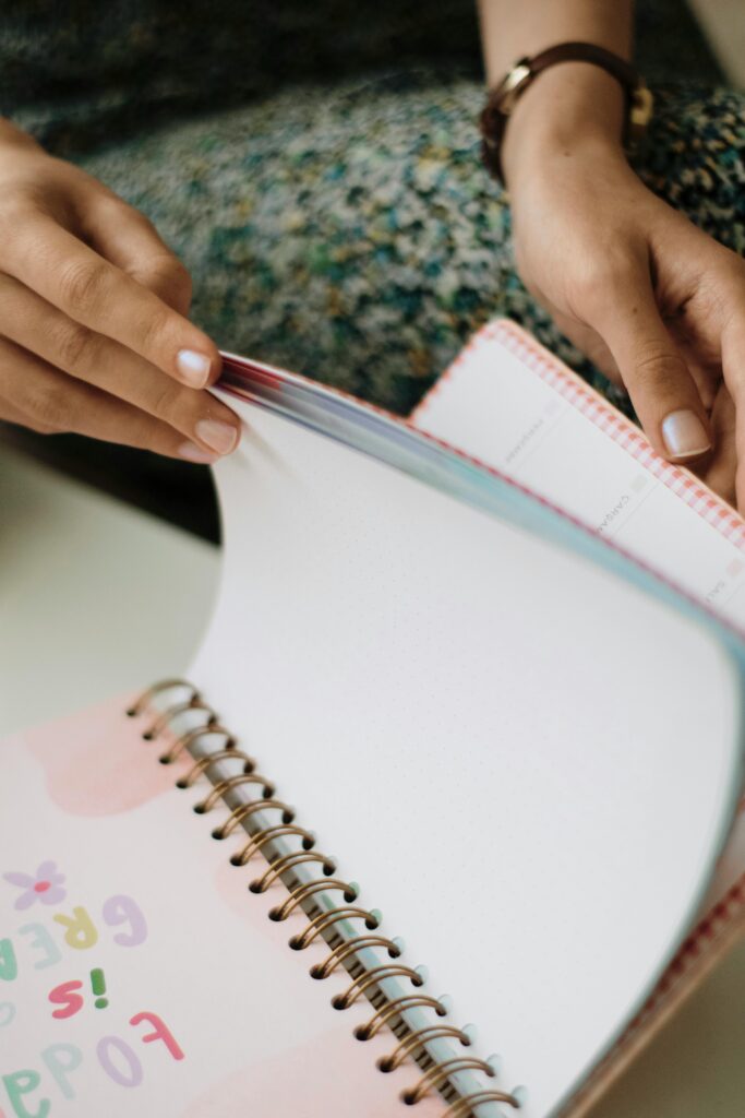 Cuaderno Mind Bloom A woman flipping through colorful pages of a planner, focused and thoughtful.