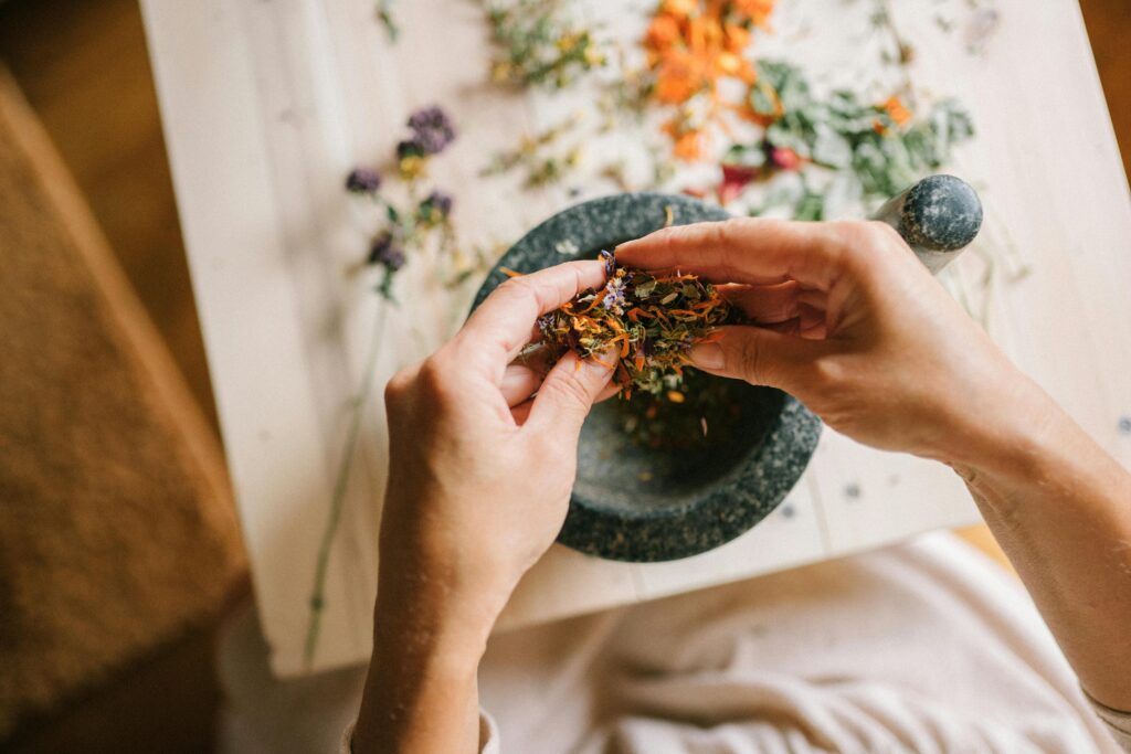 pexels-photo-5480192-5480192 Close-up of hands mixing dried herbs with a mortar and pestle for herbal medicine preparation.
