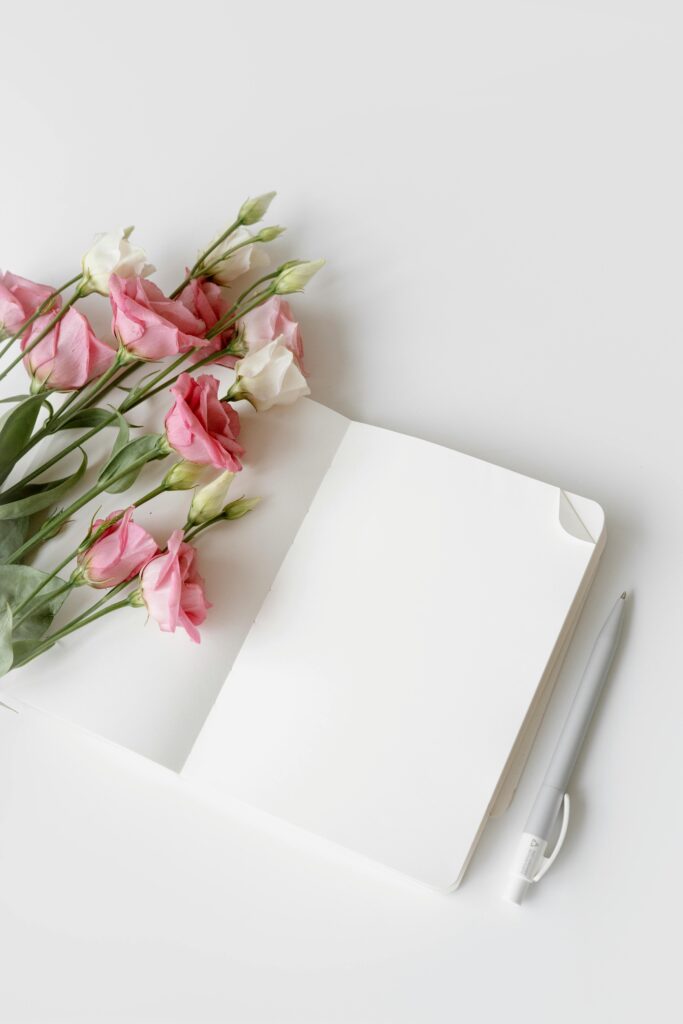 pexels-photo-8534381-8534381 Open notebook with pink and white flowers and a pen. Perfect for minimalistic designs.