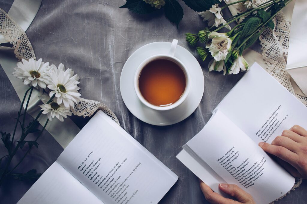 pexels-photo-904616-904616 Inviting cozy reading setup with tea, poetry books, and fresh flowers on a table.